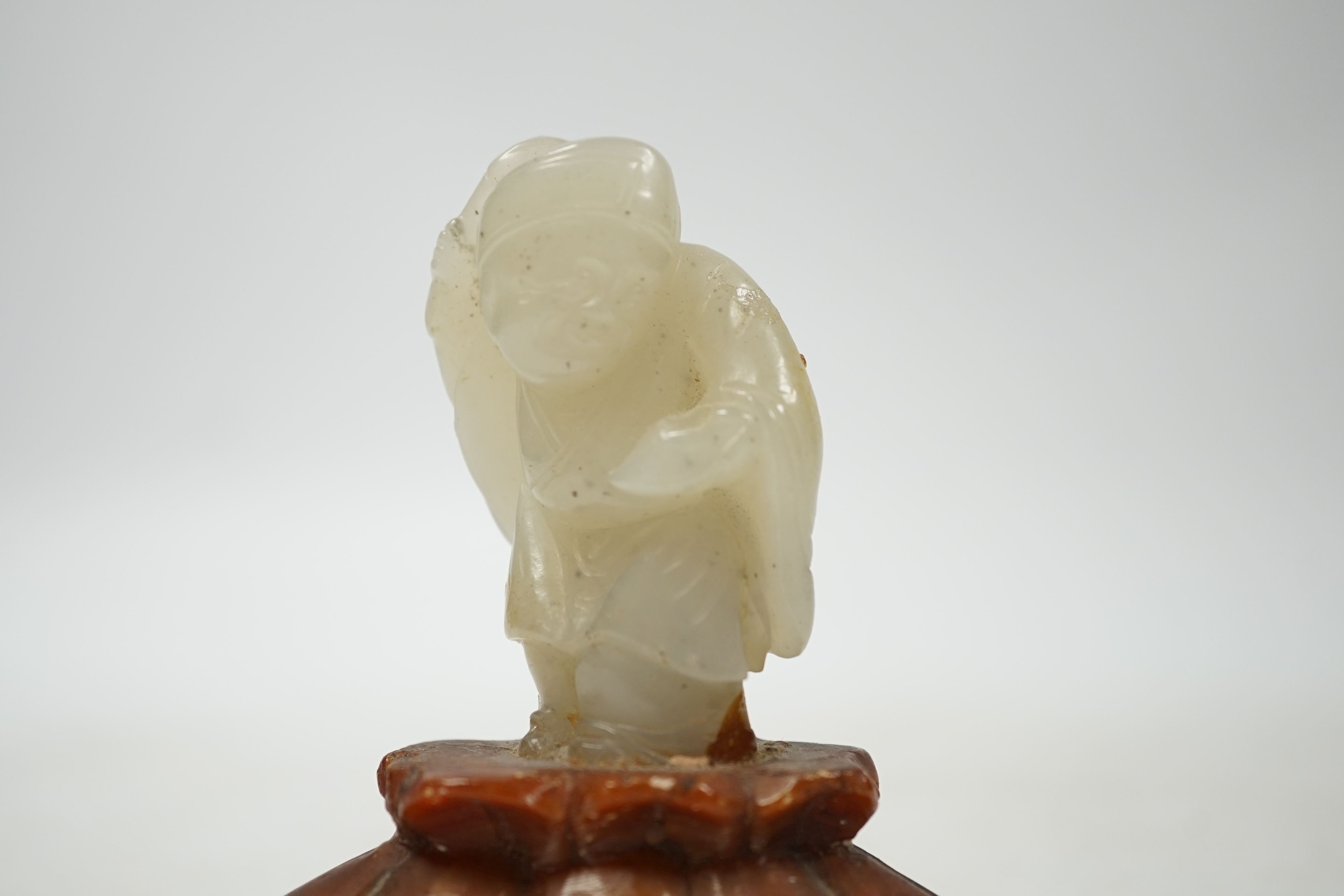 A Chinese pale celadon jade figure of a man holding a fly whisk, Qing dynasty, 5.2cm high, soapstone stand, total height 8cm high
